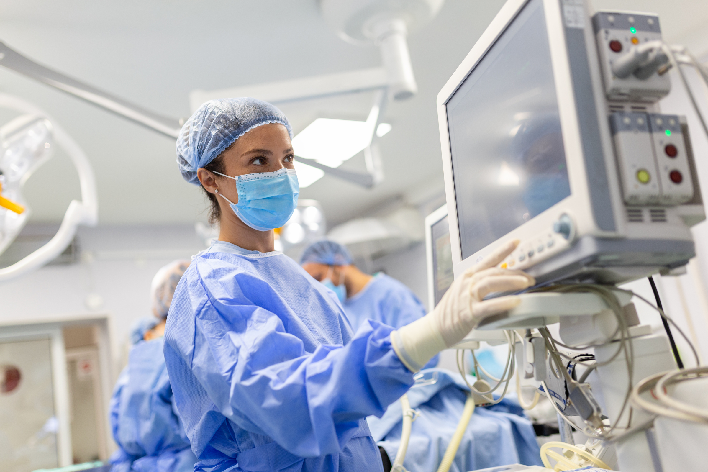 Anesthesiologist keeping track of vital functions of the body during cardiac surgery. Surgeon looking at medical monitor during surgery. Doctor checking monitor for patient health status.